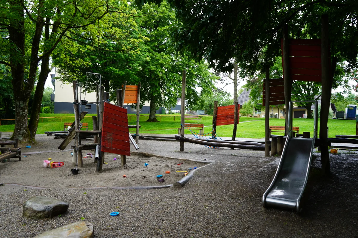 Spielplatz mit verschiedenen Spielgeräten. Rechts eine Rutschbahn.